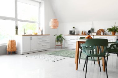 Beyaz tezgahlı ve yemek masalı modern mutfağın içi.