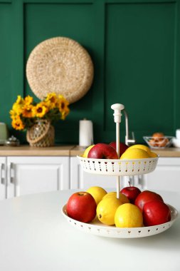 Modern mutfaktaki beyaz yemek masasında taze meyvelerle dikil.