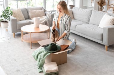 Evde çizmeleri kutuya koyan genç bir kadın.