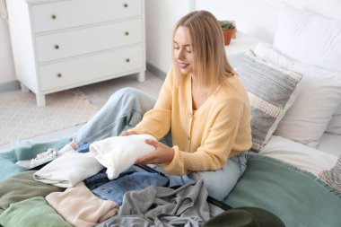 Genç bir kadın bavulunu bavula yerleştiriyor.