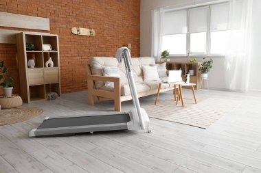 Oturma odasının içinde kanepe ve koşu bandı var.