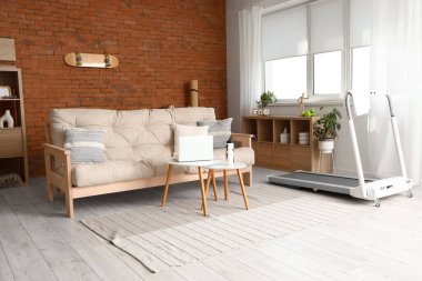 Oturma odasının içinde kanepe ve koşu bandı var.