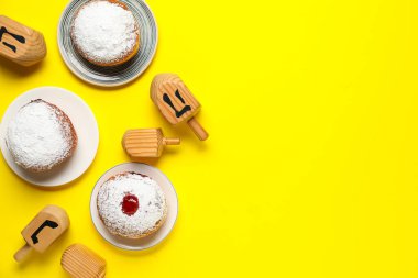 Sarı arka planda dreidel ve donut içeren Hanuka kompozisyonu