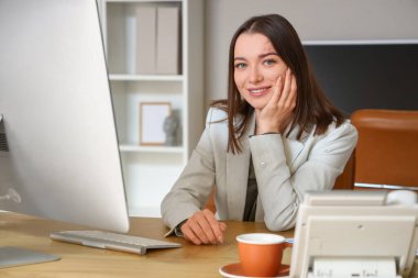 Ofiste bilgisayarla çalışan genç bir iş kadını.