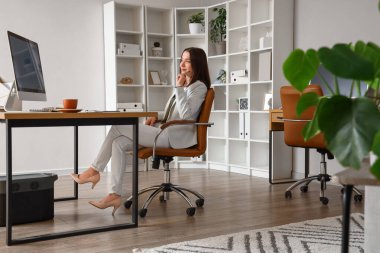 Ofiste bilgisayarla çalışan genç bir iş kadını.