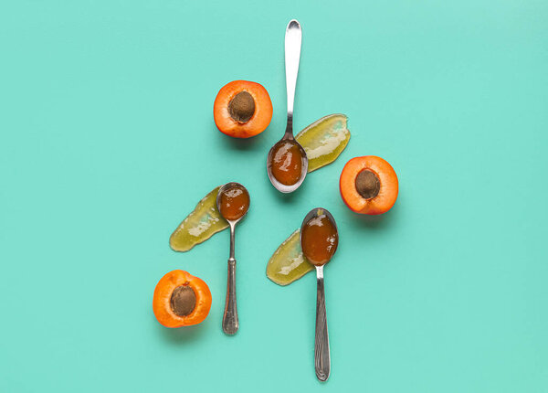 Metal spoons with sweet apricot jam on green background