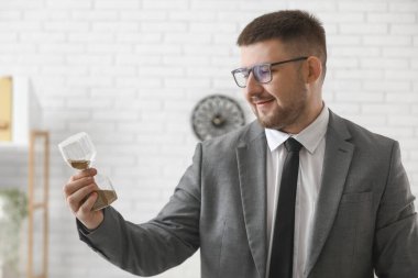 Ofisinde kum saati olan genç bir iş adamı. Zaman yönetimi kavramı