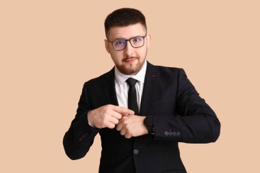 Genç işadamı bej arka planda kol saatini işaret ediyor. Zaman yönetimi kavramı