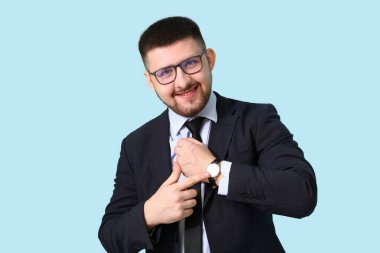 Genç mutlu iş adamı mavi arka plandaki kol saatini işaret ediyor. Zaman yönetimi kavramı