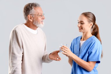 Hemşiresi olan kıdemli bir adam arka planda hap alıyor.