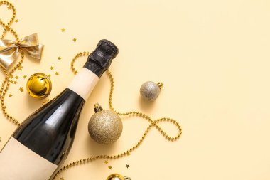 Bir şişe şampanya, Noel süslemeleri ve sarı arka planda konfeti.