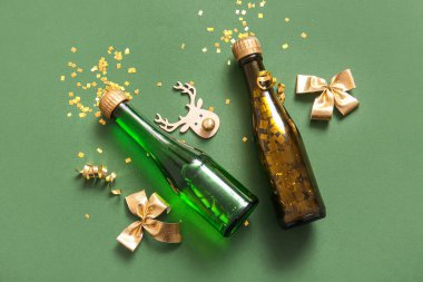 Noel süslemeli şampanya şişeleri ve yeşil arka planda konfeti.