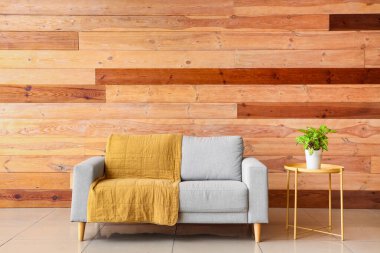 Oturma odasının içinde gri kanepe ve masa üzerinde bitki var.