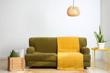 Yeşil kanepe, masa ve sepetli aydınlık oturma odasının içi.