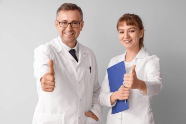 Olgun doktor ve asistanı ışık arka planında onay veriyorlar.