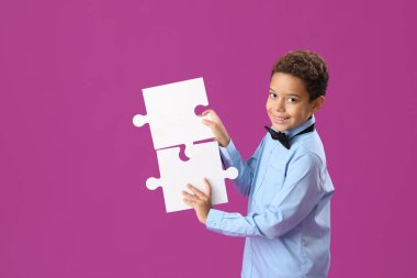 Mor arka planda yapbozları olan küçük Afro-Amerikalı çocuk.