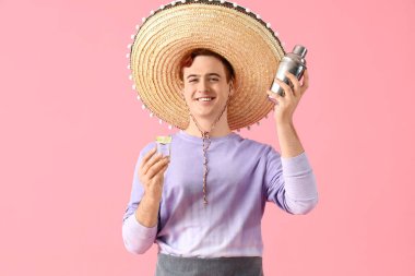 Sombrero şapkalı genç erkek barmen pembe arka planda tekila ve titretici ile