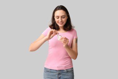 Gri arka planda açık prezervatifli güzel bir genç kadın. Güvenli seks konsepti