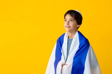 Kipa 'da sarı arka planda İsrail bayrağı taşıyan küçük bir çocuk.