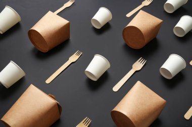 Siyah arkaplanda paket kâğıt bardaklar, kutular ve çatallar