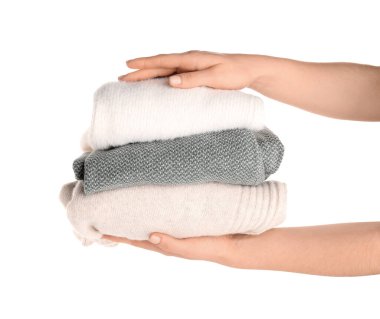 Beyaz arka planda farklı stil süveter yığını olan kadın elleri