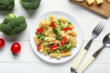 Brokolili lezzetli makarna ve beyaz ahşap arka planda domatesler.