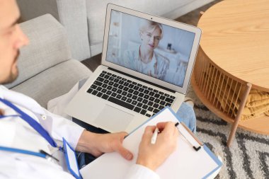 Yakışıklı doktor bilgisayarında hastayla görüntülü konuşma, yakın çekim.