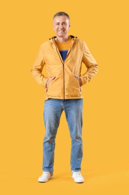 Sarı arka planda ceketli olgun bir adam.