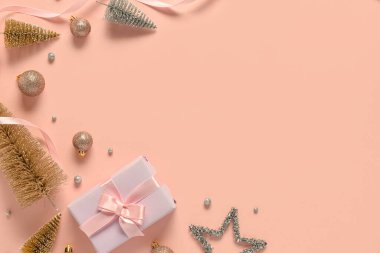 Pembe arka planda Noel süslemeleri olan hediye kutusu