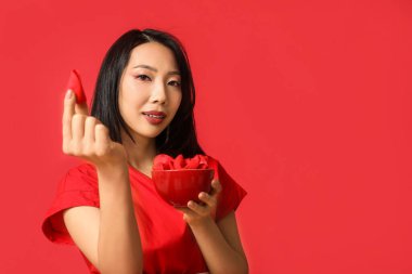 Kırmızı arka planda bir kase fal kurabiyesi olan güzel bir Asyalı kadın. Çin Yeni Yıl Kutlaması