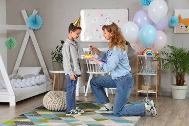 Süslü odasında küçük sevimli oğlu için doğum günü pastasıyla annesi.