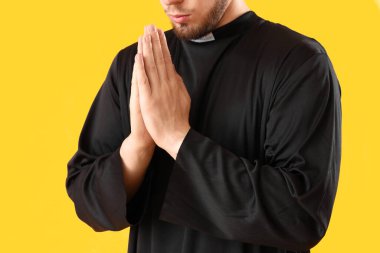 Sarı arka planda dua eden genç rahip, yakın plan.