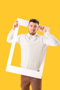 Sarı arka planda çerçeveli gözlüklü genç adam.