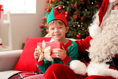 Noel hediyesi olan küçük bir elf ve evde Noel Baba