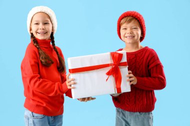 Mavi arka planda Noel hediyesi olan şirin çocuklar.