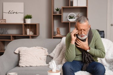 Hasta, olgun bir adam evde cep telefonuyla konuşuyor.