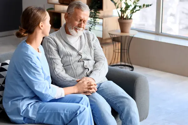 Senior man with nurse holding hands at home