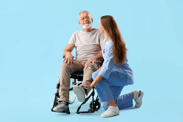 Homem Sênior Cadeira Rodas Com Enfermeira Fundo Azul — Fotografia de Stock