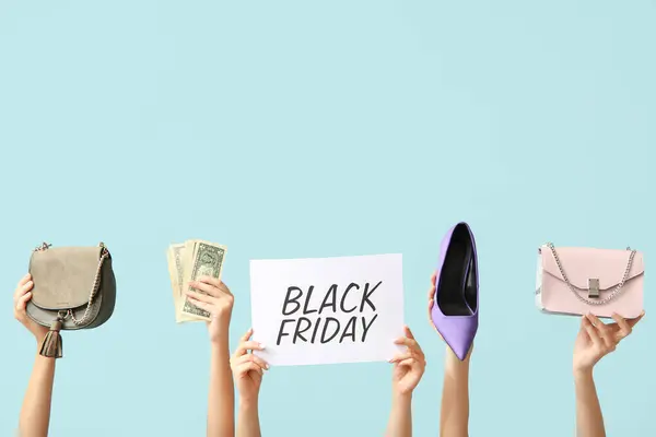 Female hands holding poster with text BLACK FRIDAY, money and women accessories on blue background