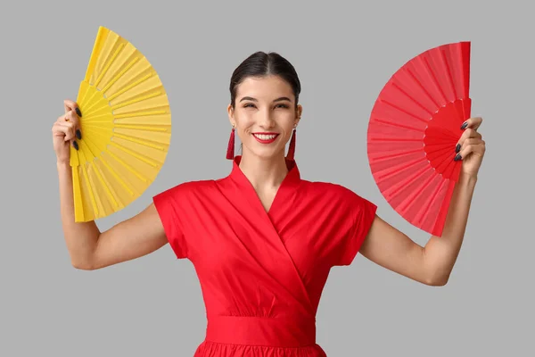 Beautiful young happy woman with fans on grey background. Chinese New Year celebration