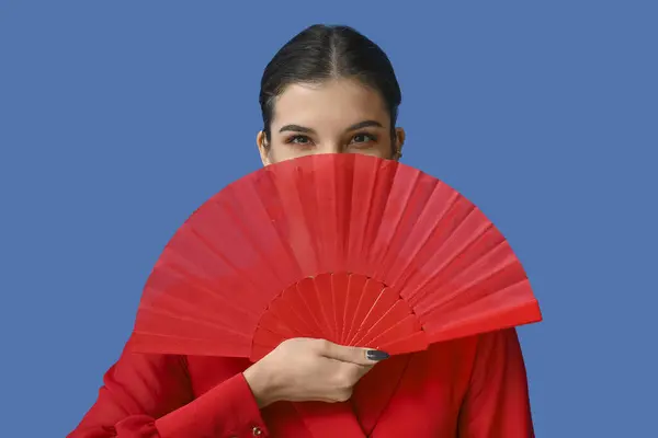 Beautiful young woman with fan on blue background. Chinese New Year celebration