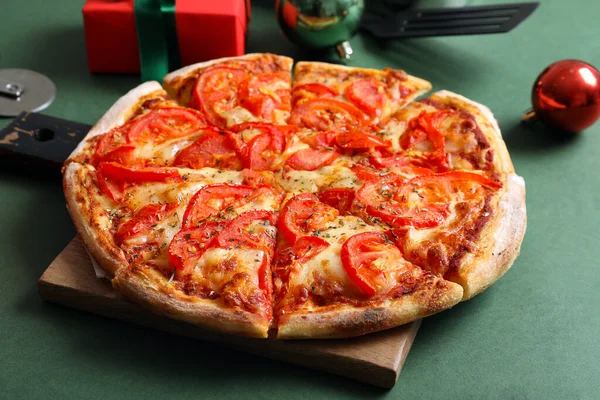Drewniana Deska Pyszną Pizzą Świątecznym Wystrojem Zielonym Tle — Zdjęcie stockowe