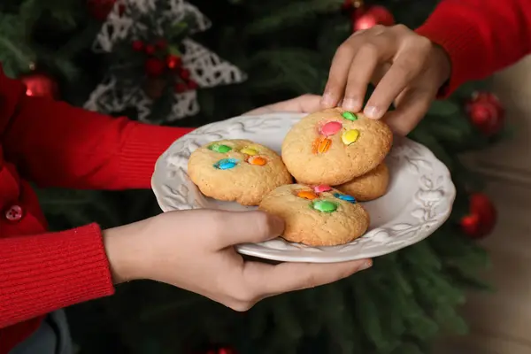 Little children eating cookies at home on Christmas eve, closeup
