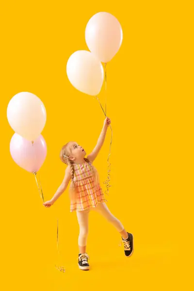 Cute little girl with beautiful balloons on yellow background