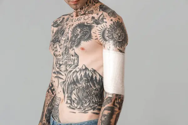 stock image Tattooed man with protective film cover on his arm against grey background