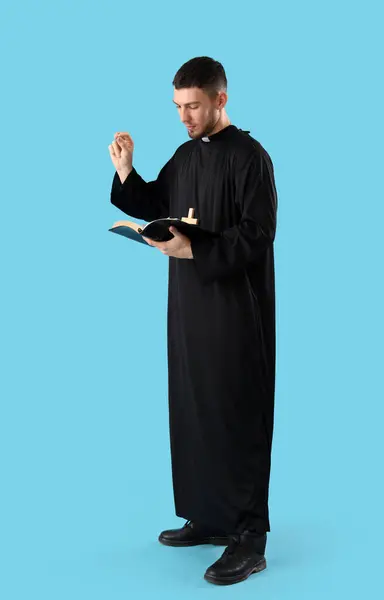 Junger Priester Mit Bibel Auf Blauem Hintergrund — Stockfoto