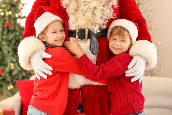 Noel arifesinde evde Noel Baba 'ya sarılan şirin çocuklar.