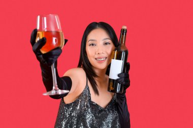 Kırmızı arka planda cam ve şarap şişesiyle güzel bir Asyalı kadın.