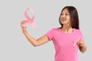 Pembe kurdeleli genç bir Asyalı kadın. Göğüs kanseri farkındalığı konsepti