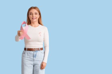 Mavi arka planda pembe kurdeleli olgun bir kadın. Göğüs kanseri farkındalığı konsepti